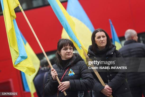 People wave the Ukraine national flag as they stand by the Cenotaph memorial in central London on the one year anniversary since the invasion of...