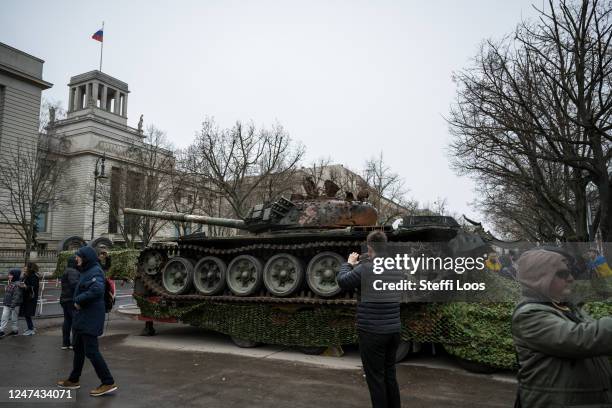 People stand in front of a destroyed Russian tank type T-72 next to the Russian embassy to commemorate the first anniversary of Russia's war in...