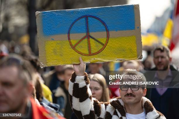 Protester holds a placard bearing the Ukrainian colours and the peace symbol during a "March of Solidarity and Peace", organised by the Ukrainian...