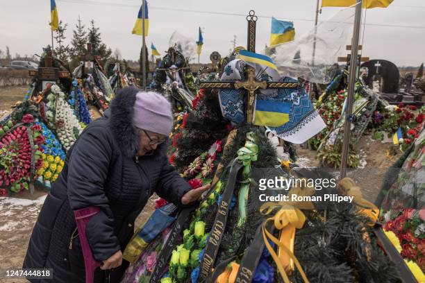 Mariia, a mother of a killed in Bakhmut Ukrainian soldier Vasyl Kurbyt, grieves at his grave at a cemetery, as Ukraine marks one year since Russia's...