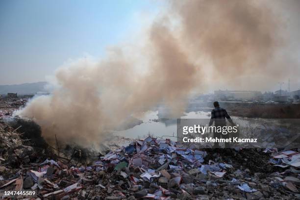 Man stands next to a hole where waste is being burnt on February 24, 2023 in Hatay, Turkey. A 7.8-magnitude earthquake hit near Gaziantep, Turkey, in...