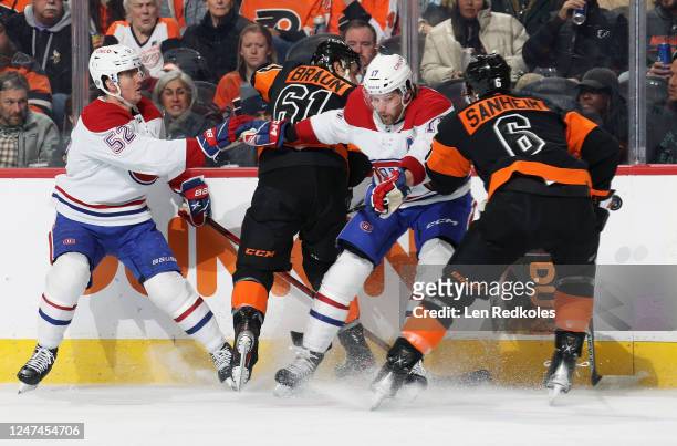 Justin Braun and Travis Sanheim of the Philadelphia Flyers crash into the boards with Justin Barron and Josh Anderson of the Montreal Canadiens as...