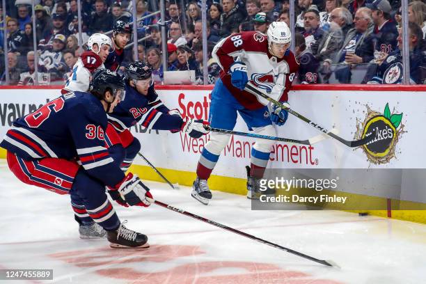 Andreas Englund of the Colorado Avalanche plays the puck along the boards away from Karson Kuhlman and Morgan Barron of the Winnipeg Jets during...
