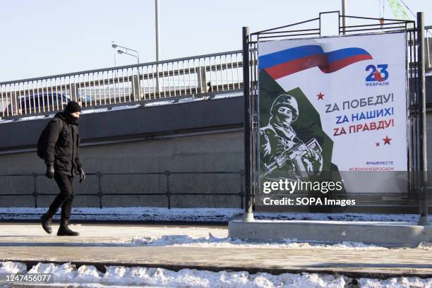 Man walks past a propaganda poster that reads "For victory! For our people! For the truth" in Moscow during the Defender of the Fatherland Day....