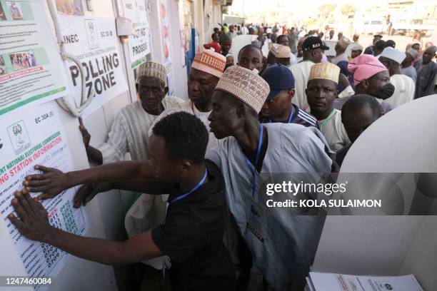 Party agents look at a poster with polling station information on in Kano on February 25 during Nigeria's presidential and general election.