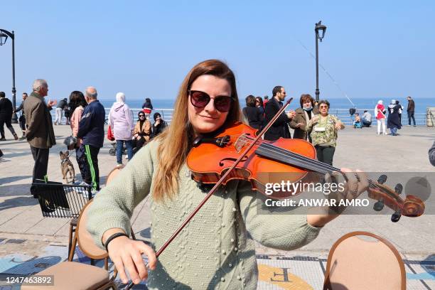 Musician from the Italian Orchestra della Magna Grecia, plays her violin following a performance at the seaside corniche in Beirut on February 25 as...
