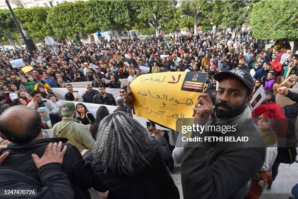 Protesters lift placards during a demonstration in Tunis on February 25 against controversial remarks by the Tunisian President regarding illegal...