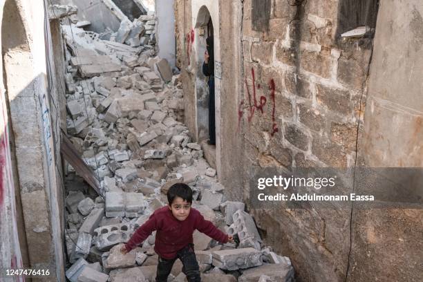 Child walks out from his destroyed house, the local council let a mark on the wall, "evacuation", to inform the family that they can't stay here...