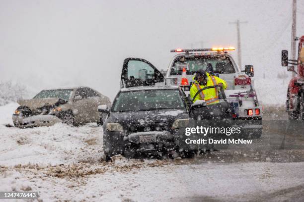 Wrecked car is towed from a snowy ditch along Sierra Highway on February 25, 2023 near Acton, California. The National Weather Service issued a...