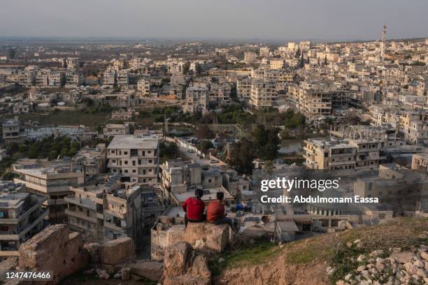 Two young Syrians sit at the Castel of Harim, the old military Castel dated to 959 AD was a bit damaged by the earthquake, enjoying the sunset and...