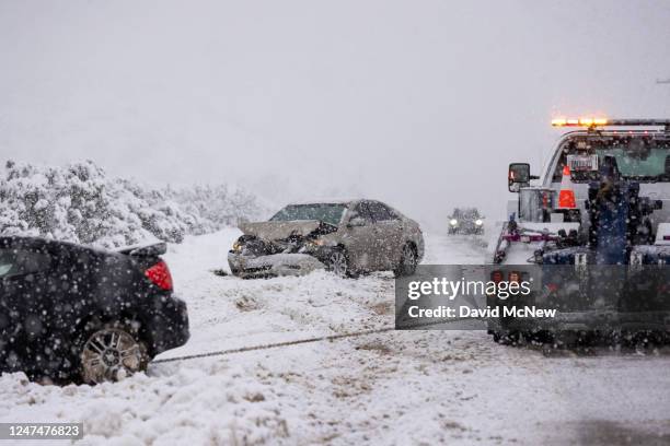 Wrecked car is towed from a snowy ditch along Sierra Highway on February 25, 2023 near Acton, California. The National Weather Service issued a...