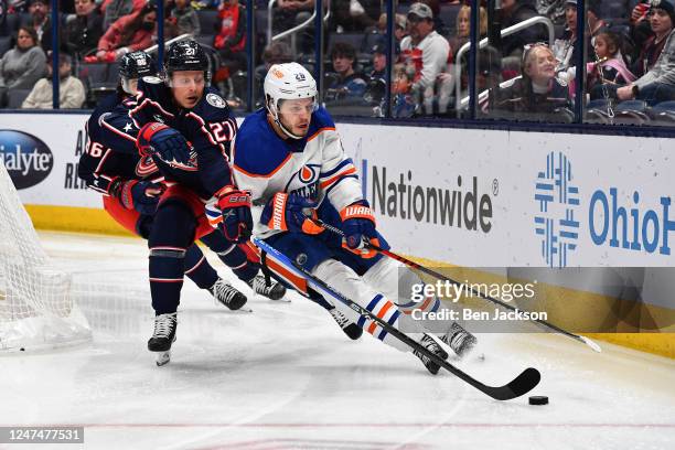 Adam Boqvist of the Columbus Blue Jackets and Mattias Janmark of the Edmonton Oilers battle for a loose puck during the second period of a game at...