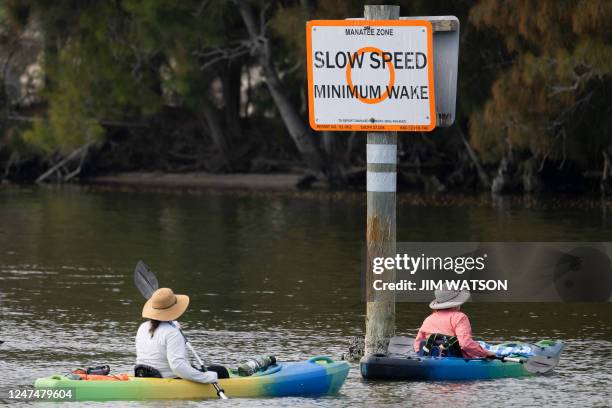 Kayakers pass a sign warning of manatees in the area within Bairs Cove at Merritt Island National Wildlife Refuge in Titusville, Florida, on February...
