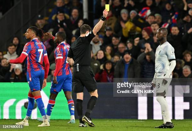 Referee Darren England shows a yellow card to Liverpool's Guinean midfielder Naby Keita during the English Premier League football match between...