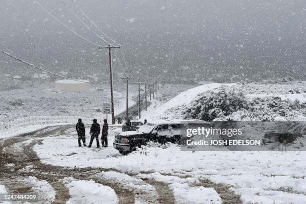 Local residents watch as vehicles attempt to navigate an icy road in Rancho Cucamonga, California, on February 25, 2023. - Heavy snow fell in...