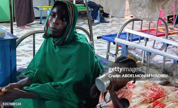 Woman and a child sit waiting at a nutrition centre at the Kalma camp for the displaced just outside Nyala, the provincial capital of South Darfur...