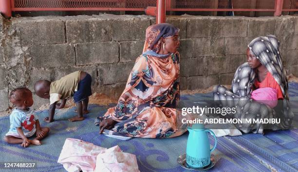 Women and a children sit waiting outside a nutrition centre at the Kalma camp for the displaced just outside Nyala, the provincial capital of South...