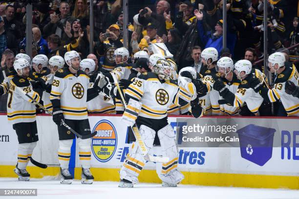 Linus Ullmark of the Boston Bruins is congratulated at the player's bench after scoring a goal into an empty net against the Vancouver Canucks during...