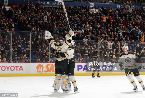 Linus Ullmark of the Boston Bruins is congratulated by teammate Brandon Carlo after scoring a goalie goal during their NHL game against the Vancouver...