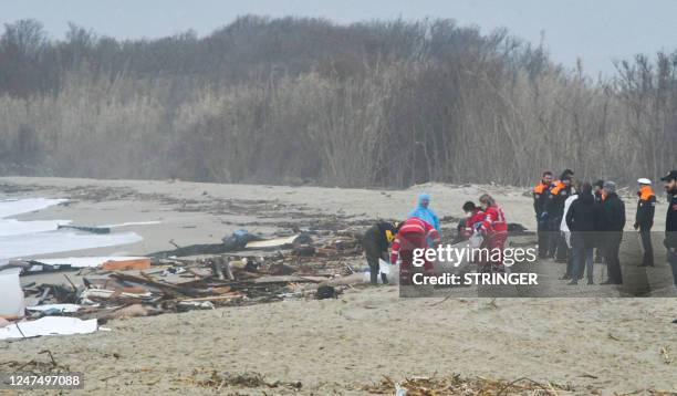 This photo obtained from Italian news agency Ansa, taken on February 26, 2023 shows rescuers handling a body bag at the site of a shipwreck in...