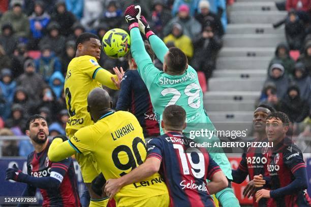 Inter Milan's Dutch midfielder Denzel Dumfries and Bologna's Polish goalkeeper Lukasz Skorupski go for the ball during the Italian Serie A football...