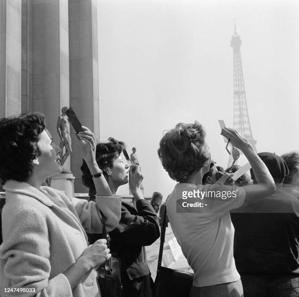 Parisians observe the total solar eclipse using smoked glasses, from the Trocadero esplanade on October 2, 1959 in Paris.