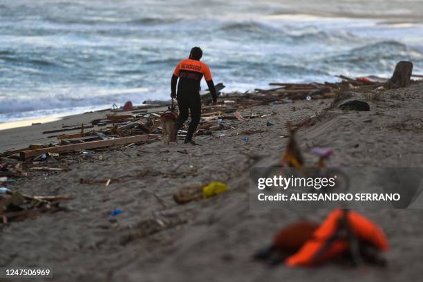 Member of the cynophile police and his dog patrol the beach on February 26, 2023 in Steccato di Cutro, south of Crotone, where debris of a shipwreck...