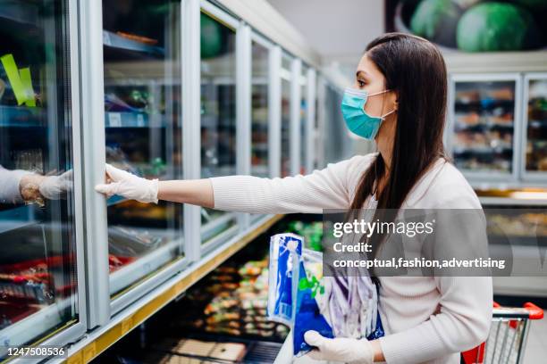 woman with hygienic mask shopping for supply.budget buying at a supply store.emergency to buy list.shopping for enough food and cleaning products.preparation for a pandemic quarantine due to covid-19 - expiry date stock pictures, royalty-free photos & images