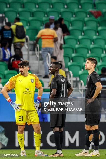 Duhail's Qatari goalkeeper Salah Zakaria, Qatari forward Almoez Ali, and Argentine defender Federico Fernandez stand on the pitch after the end of...