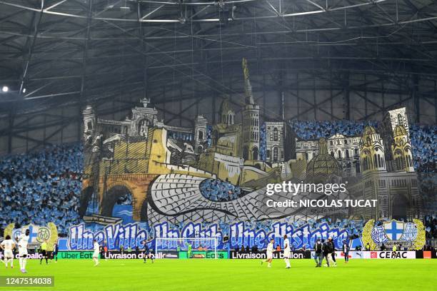 Players warm up in front of the tifo, featuring "Notre Dame de la Garde" in the south wing of the supporters before the French L1 football match...