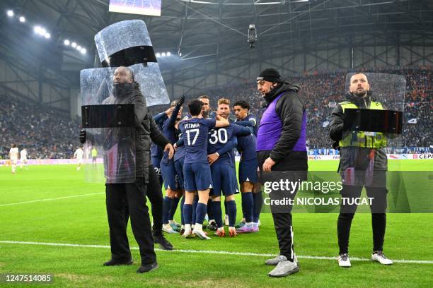 Paris Saint-Germain's players celebrate after Argentine forward Lionel Messi scored as security staff stand guard on the picth during the French L1...