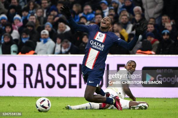 Paris Saint-Germain's Portuguese defender Nuno Mendes falls in front of Marseille's Portuguese defender Nuno Tavares during the French L1 football...