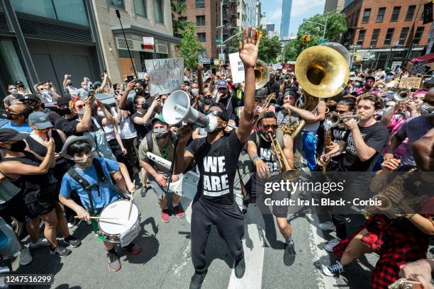 Musician Jon Batiste holds up his hands while his band jams for the crowd of people that have followed him onto to 6th Avenue from Union Square for a...