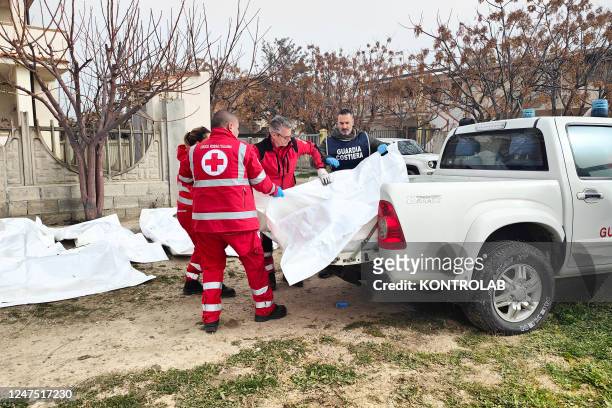 Red Cross volunteers and Coast Guard agents deposit the bodies of migrants in white bags in a collection area for the dead in the shipwreck. In...