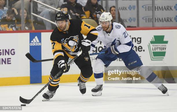 Bryan Rust of the Pittsburgh Penguins skates with the puck under pressure from Brayden Point of the Tampa Bay Lightning in the first period during...