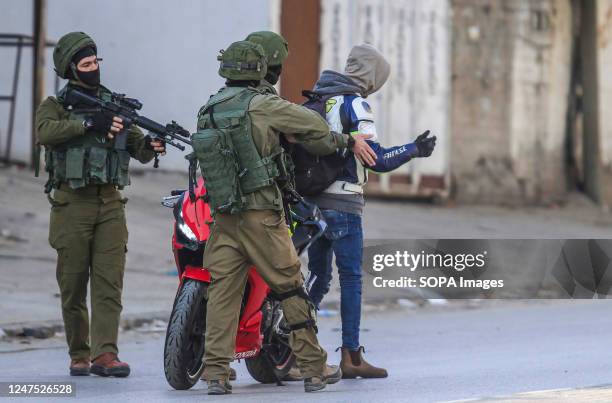 Israeli soldiers arrest a Palestinian as they secure the area near the place where two Israeli settlers were killed near the town of Hawara, south of...