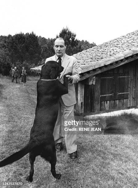 François Mitterrand, premier secrétaire du parti socialiste, joue avec son chien dans le parc de sa propriété de "Latché" près de Soustons, dans les...