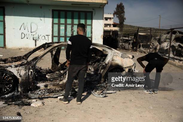 Palestinian men stand near a burned house after settlers riot and set houses and cars on fire in the village of Hawara on February 27, 2023 in...