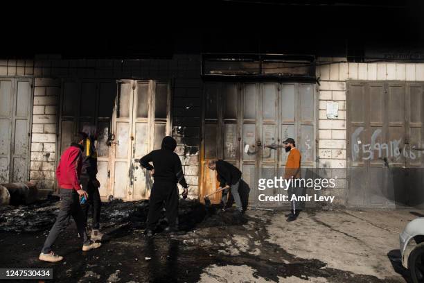 Palestinian men work near a burned house after settlers riot and set houses and cars on fire in the village of Hawara on February 27, 2023 in Hawara,...