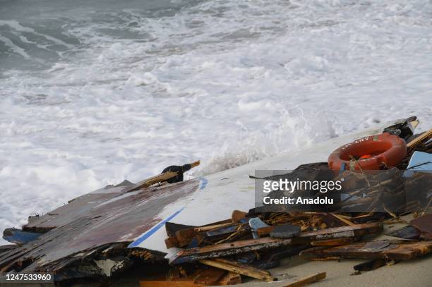 The wreckage of the ship carrying the immigrants and a life buoy are seen on the beach as search and rescue operations continue to find about 20...