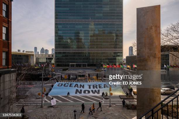 Activists from Greenpeace display a banner before the United Nations headquarters during ongoing negotiations at the UN on a treaty to protect the...