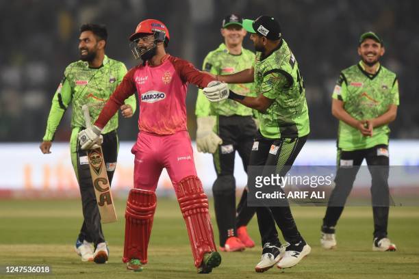Islamabad United's captain Shadab Khan walks off the pitch after his dismissal as Lahore Qalandars' cricketers celebrate during the Pakistan Super...