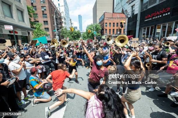 Dancers take the rhythm from Musician Jon Batiste and his band jams for the crowd of people that have followed him onto to 6th Avenue from Union...