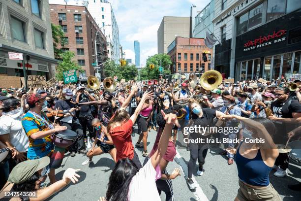 Dancers take the rhythm from Musician Jon Batiste and his band jams for the crowd of people that have followed him onto to 6th Avenue from Union...