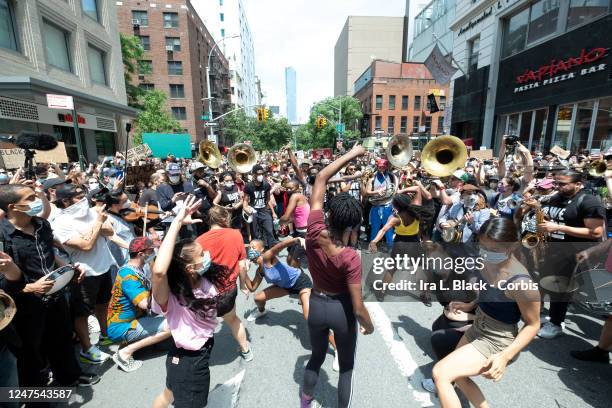 Dancers take the rhythm from Musician Jon Batiste and his band jams for the crowd of people that have followed him onto to 6th Avenue from Union...