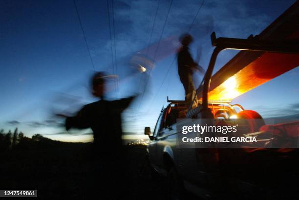 Workers get the necessary tools to remove a glass insulator from an energy tower to replace it for an organic one, 21 October 2003 on the outskirts...