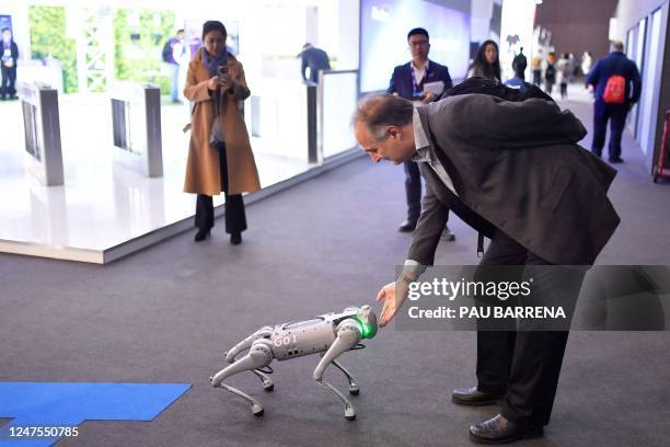 An attendee touches the dog-shaped Robot Go1 by Unitree at the Mobile World Congress , the telecom industry's biggest annual gathering, in Barcelona...