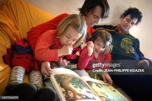 French 19-year-old couple Myriam Blanc and Astrid Boekholt read a book 19 October 2005 with their daughters Augustine and Assia, 4. The two girls of...