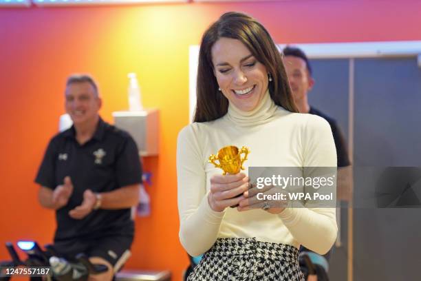 Catherine, Princess of Wales looks after her winner's trophy after beating Prince William, Prince of Wales at a spin class during a visit to Aberavon...