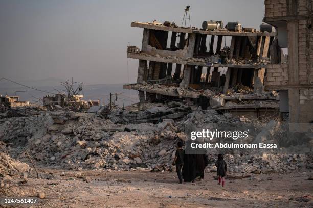 Family walks through destroyed buildings in the city of Jindires on February 28, 2023 near Aleppo, Syria. A 7.8-magnitude earthquake hit near...